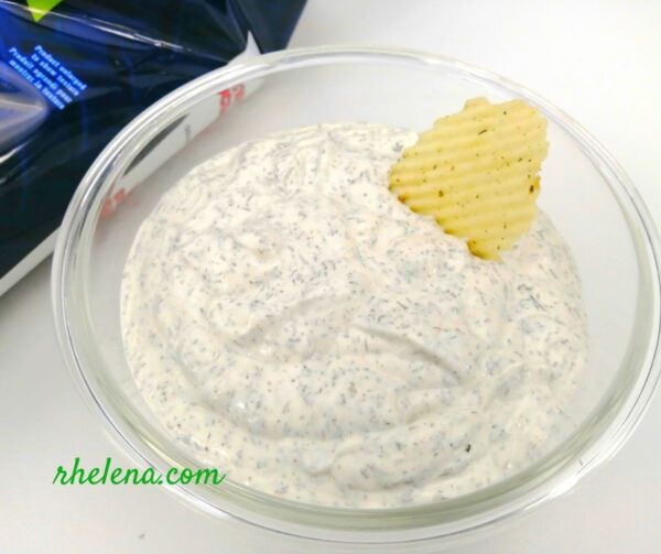 A dill dipping sauce shown in a bowl along with a potato chip. The dill dip recipe is quick and easy to make.