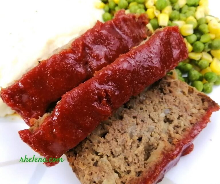 Sliced meatloaf shown with peas and corn.